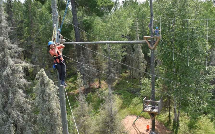 a group of outward bound students make their way through a high ropes course